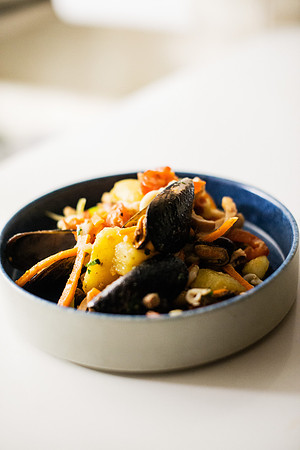 Creative seafood pasta dish served in a blue bowl on a white cou