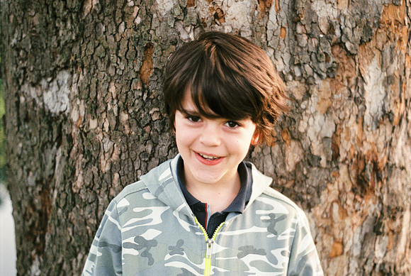 portrait of a 10 year old boy leaning against a large plane-tree