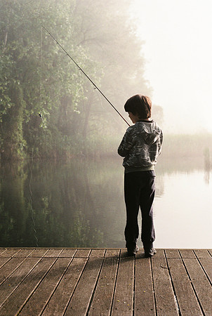 10-year-old boy fishing at dawn on Lake Varese Italy
