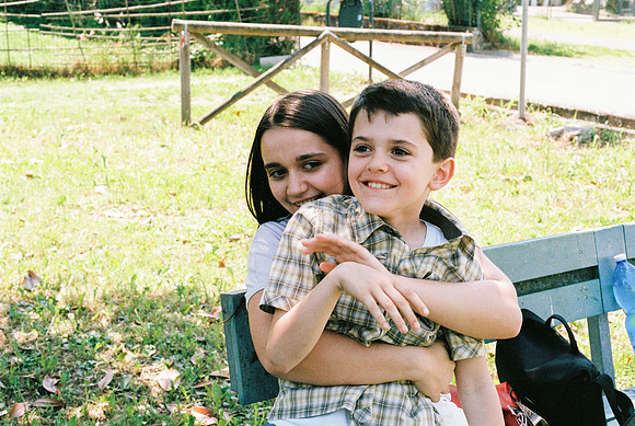 brother and sister hugging each other, sitting on the bench